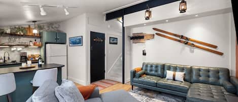 A modern living space with a kitchen, dining area, and a large gray sofa.