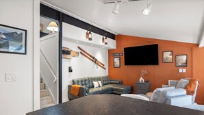 A modern living room with a sectional sofa, a flat-screen TV, and a staircase leading to another level. - Ascend Remodeled Condo, SummerFun, Bear&Alpine Lake, across musical festival (Bear Valley)