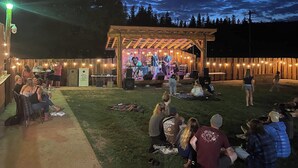 A covered outdoor stage with a band performing, surrounded by a crowd of people. - Ascend Remodeled Condo, SummerFun, Bear&Alpine Lake, across musical festival (Bear Valley)