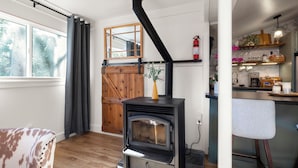 A cozy kitchen with a wood-burning stove, a wooden door, and a window with curtains. - Ascend Remodeled Condo, SummerFun, Bear&Alpine Lake, across musical festival (Bear Valley)