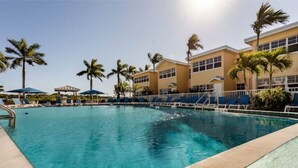 Une piscine avec des chaises longues et des palmiers.