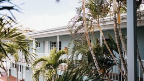 Un bâtiment à la façade bleu clair, doté de nombreux balcons et bordé de palmiers.