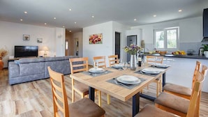 Un salon moderne comprenant un coin repas, une cuisine et un téléviseur.