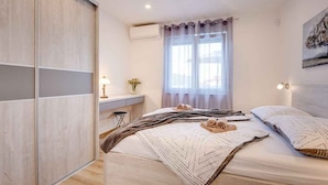 Une chambre à coucher avec un lit, une table de chevet et une fenêtre avec des rideaux.
