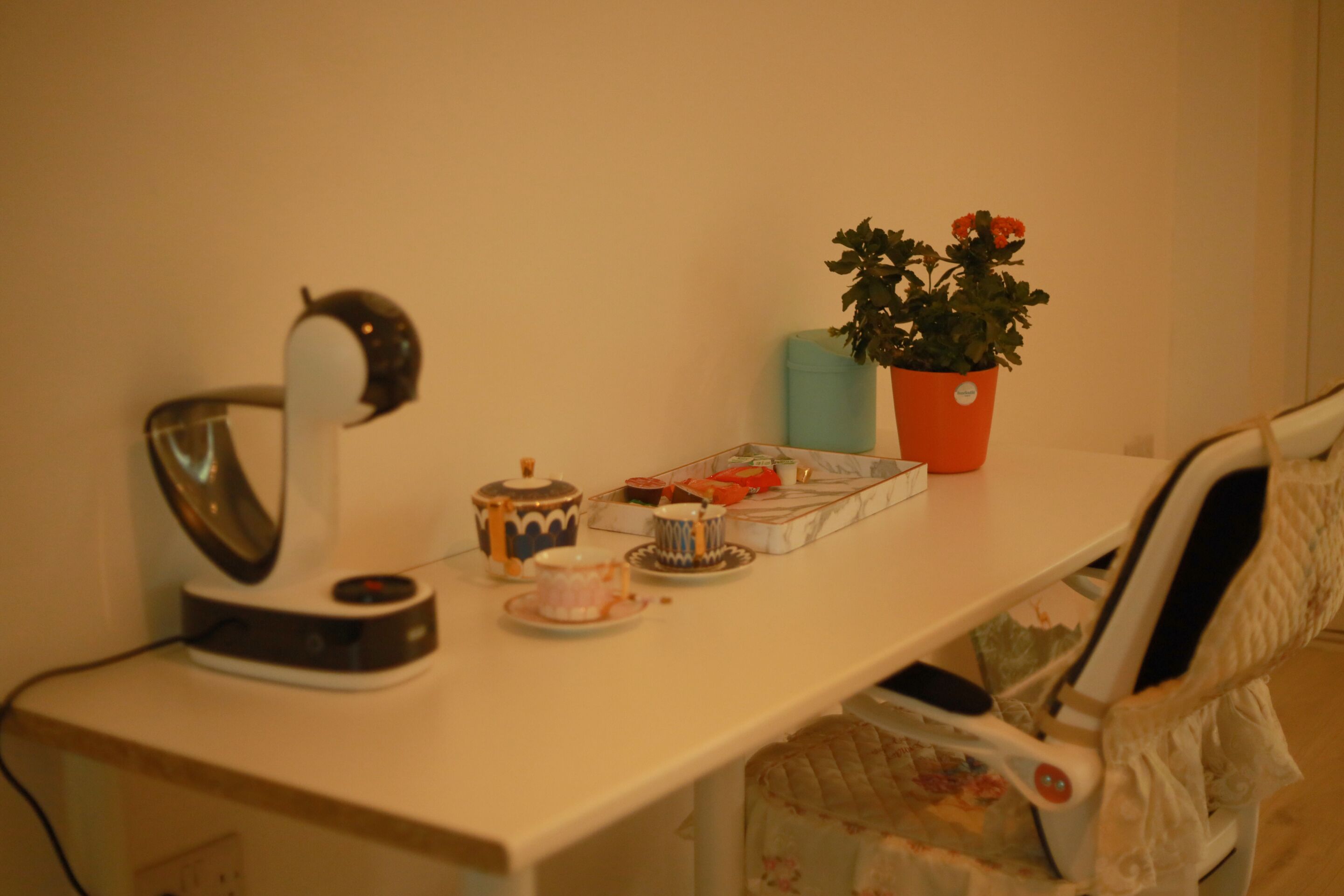 A desk with a kettle, teapot, cups, and a potted plant.