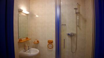 Baño con ducha de vidrio, lavabo y espejo.