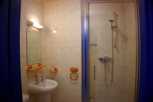 Baño con ducha de vidrio, lavabo y espejo.