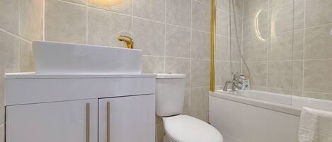 Un baño moderno con lavamanos, inodoro y bañera blancos.