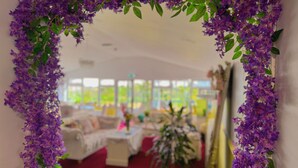 A room with a purple floral arch, a sofa, a coffee table, and a potted plant. - The Evergreen hotel (Banbury)