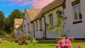 A row of white buildings with green shutters and a sloped roof. - The Evergreen hotel (Banbury)