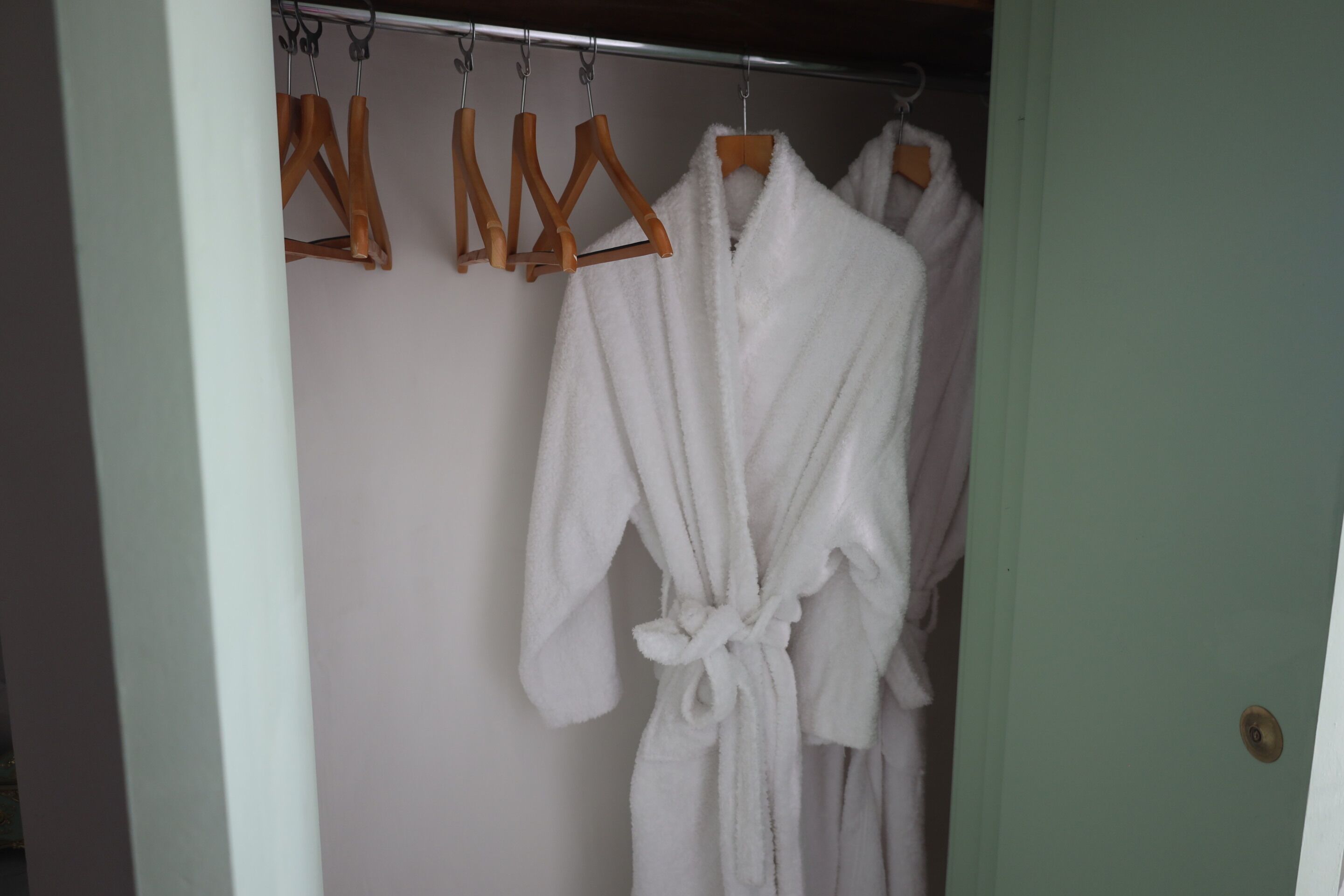 A bathroom with a white bathtub, a towel rack with wooden hangers, and a green door.