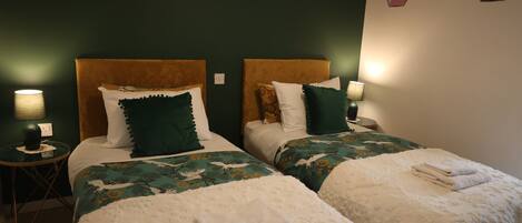 Habitación de hotel con dos camas, cada una con cabecero, mesitas de noche, lámparas y cojines decorativos.