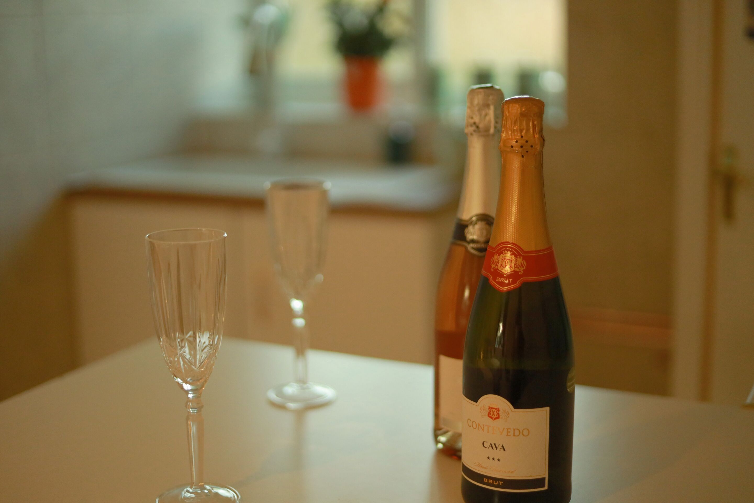 Een fles Cava en twee glazen op een tafel.