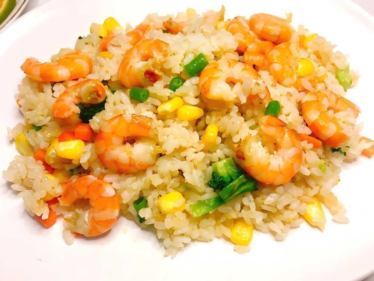 Une assiette de riz frit aux crevettes et aux légumes.