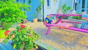 A garden area with a wooden bench, potted plants, and a table with a pink tablecloth. - The Evergreen hotel (Banbury)