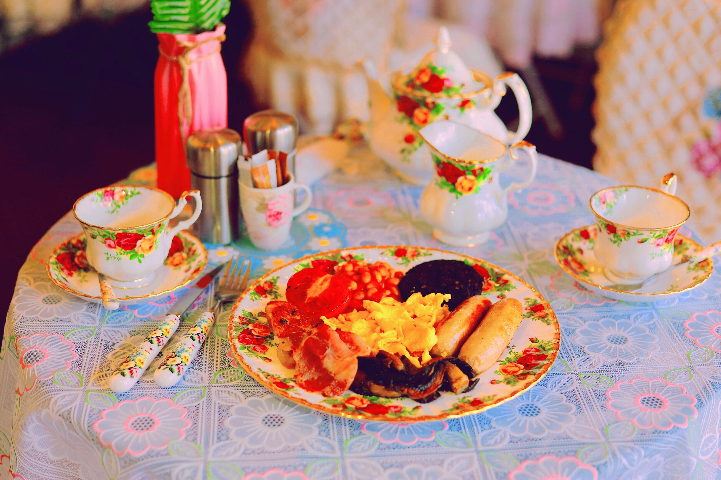 A table set with floral-patterned tea service, plates of food, and silverware.