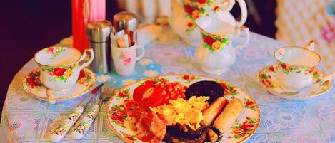 A table set with floral-patterned tea service, plates of food, and silverware.
