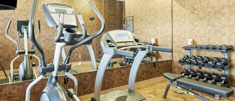 Un gimnasio con cintas de correr, elípticas y una prensa de pesas.