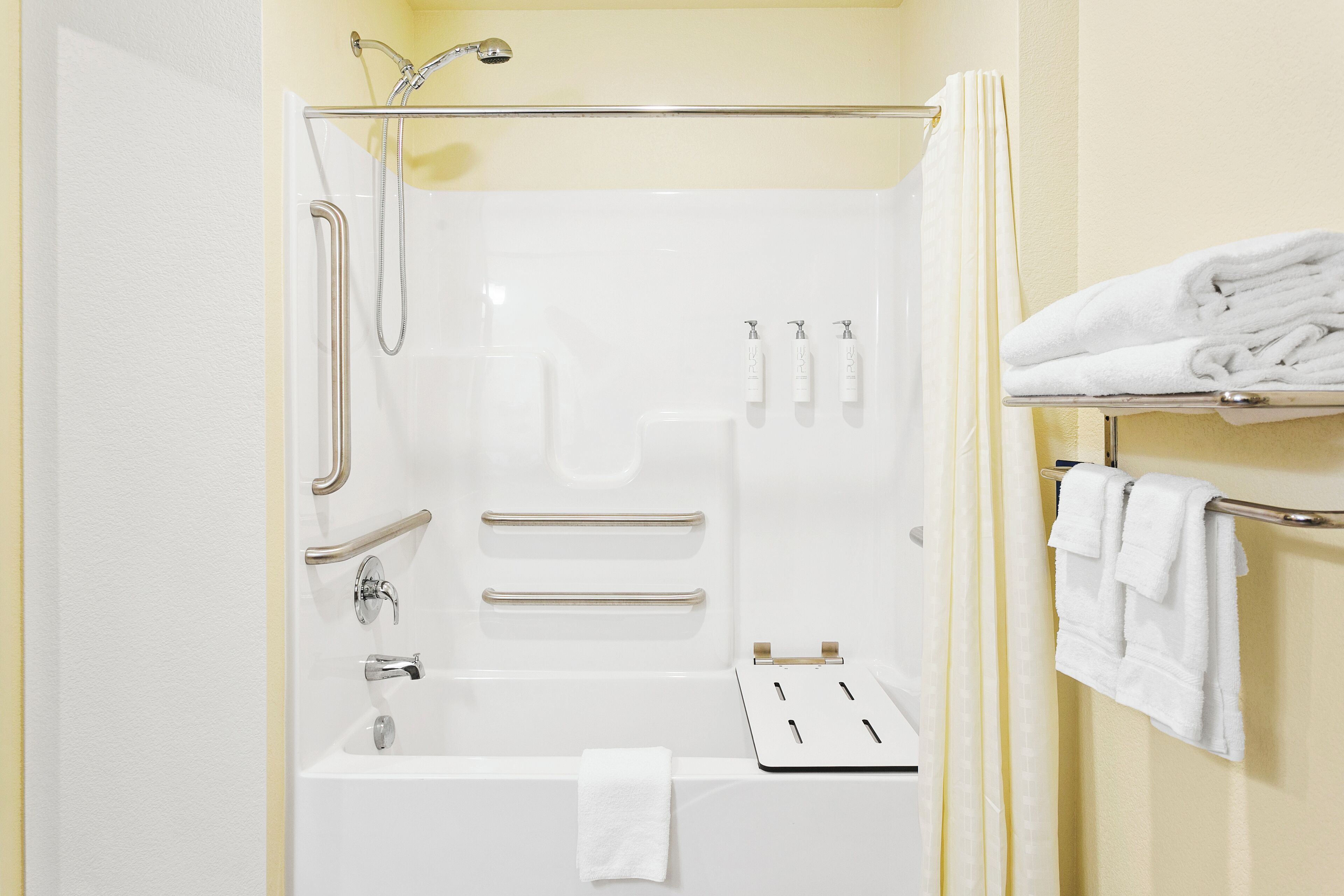 A modern bathroom with a glass-enclosed shower, a bathtub, and a towel rack with folded towels.