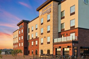 A hotel with a modern brick facade, multiple windows, and outdoor seating area. - Cobblestone Hotel & Suites - Wickenburg (Wickenburg)