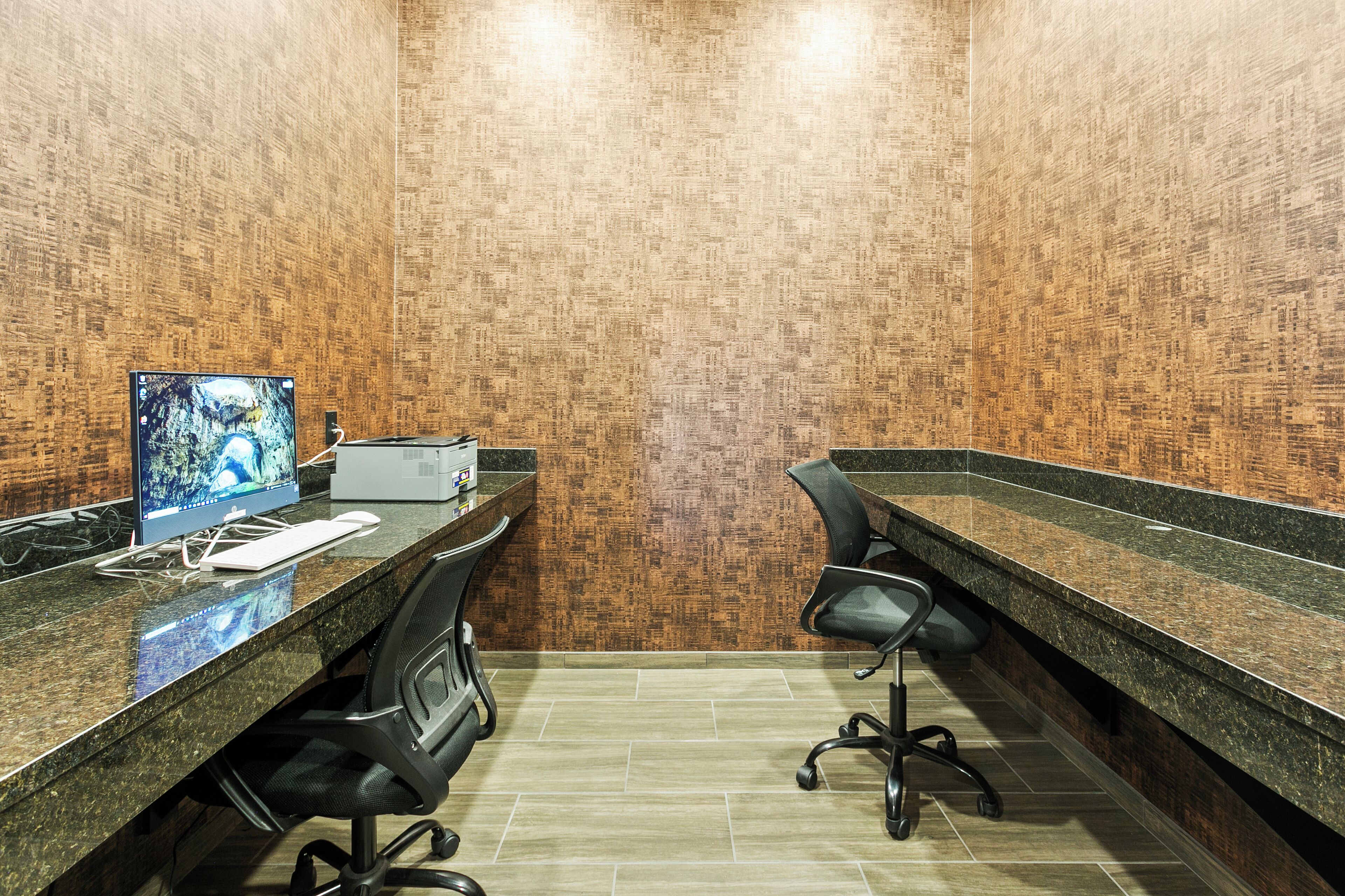 A modern office space with two desks, chairs, a computer, and a printer.