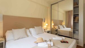 Una habitación de hotel con una cama grande, un armario y una mesita de noche con lámpara.