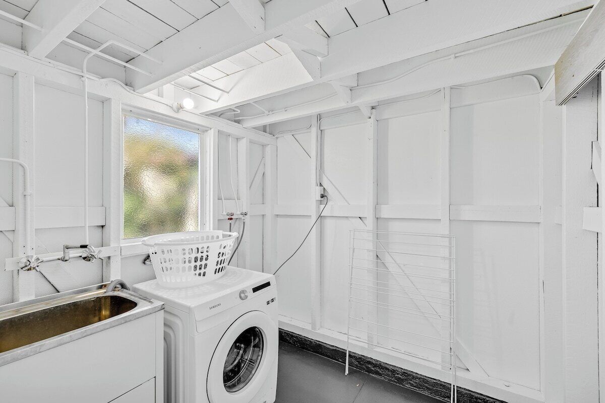Une buanderie équipée d’un lave-linge, d’un évier et d’une fenêtre.