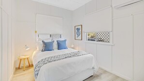 A bedroom with a bed, bedside tables, a window with a view, and a ceiling light. - Sage Cottage! CBD Perfection! (East Toowoomba)