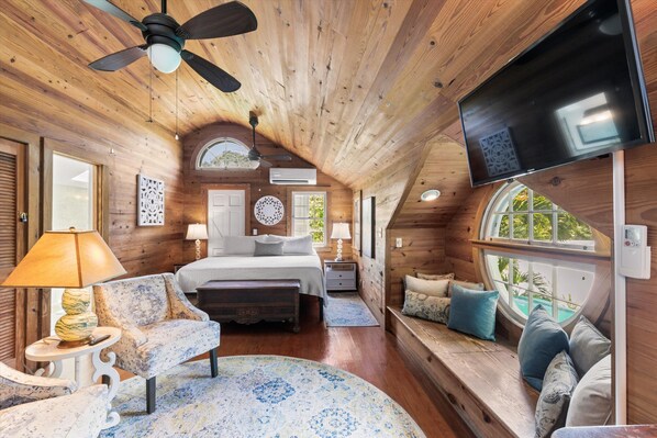 A cozy cabin interior with a bed, seating area, and a TV. - William Skelton Home - Sleeps 16 just off Duval St (Key West)