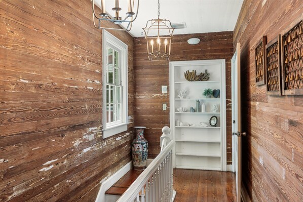 A wooden interior with a white door, a white railing, and a chandelier. - William Skelton Home - Sleeps 16 just off Duval St (Key West)