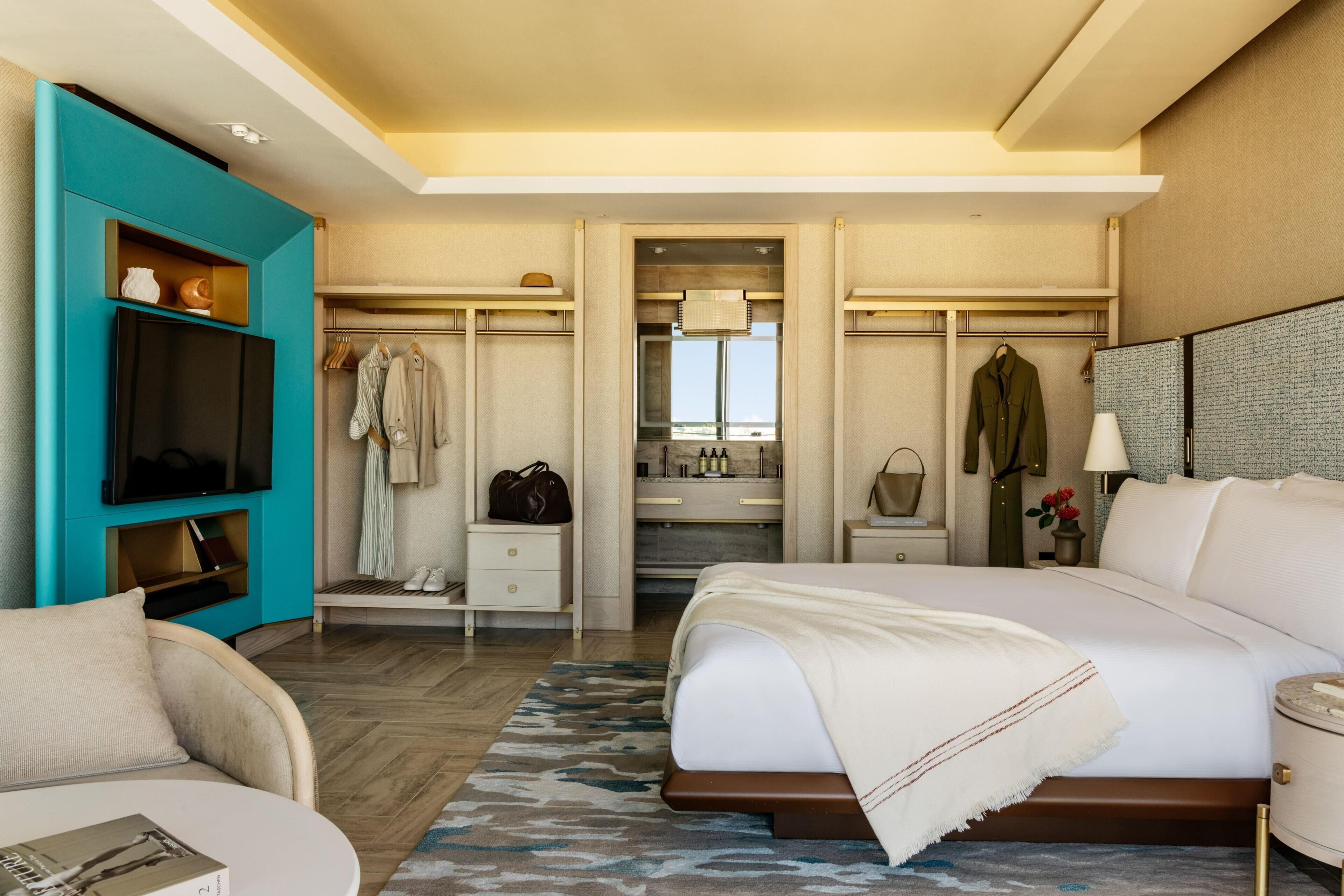 Quarto de hotel com cama, televisão, armário, banheiro e vista.