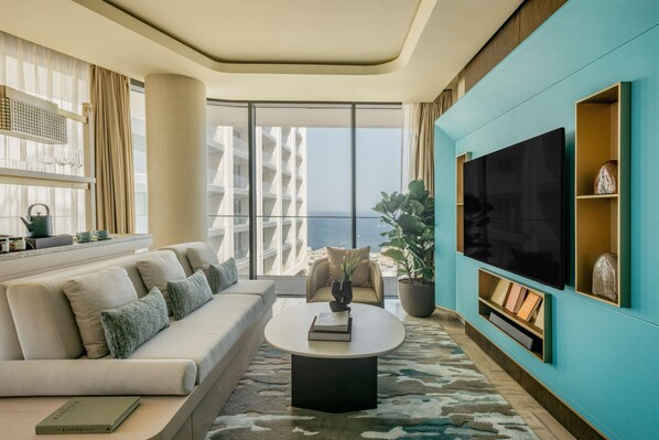 A modern living room with a sofa, coffee table, and a large flat-screen TV.