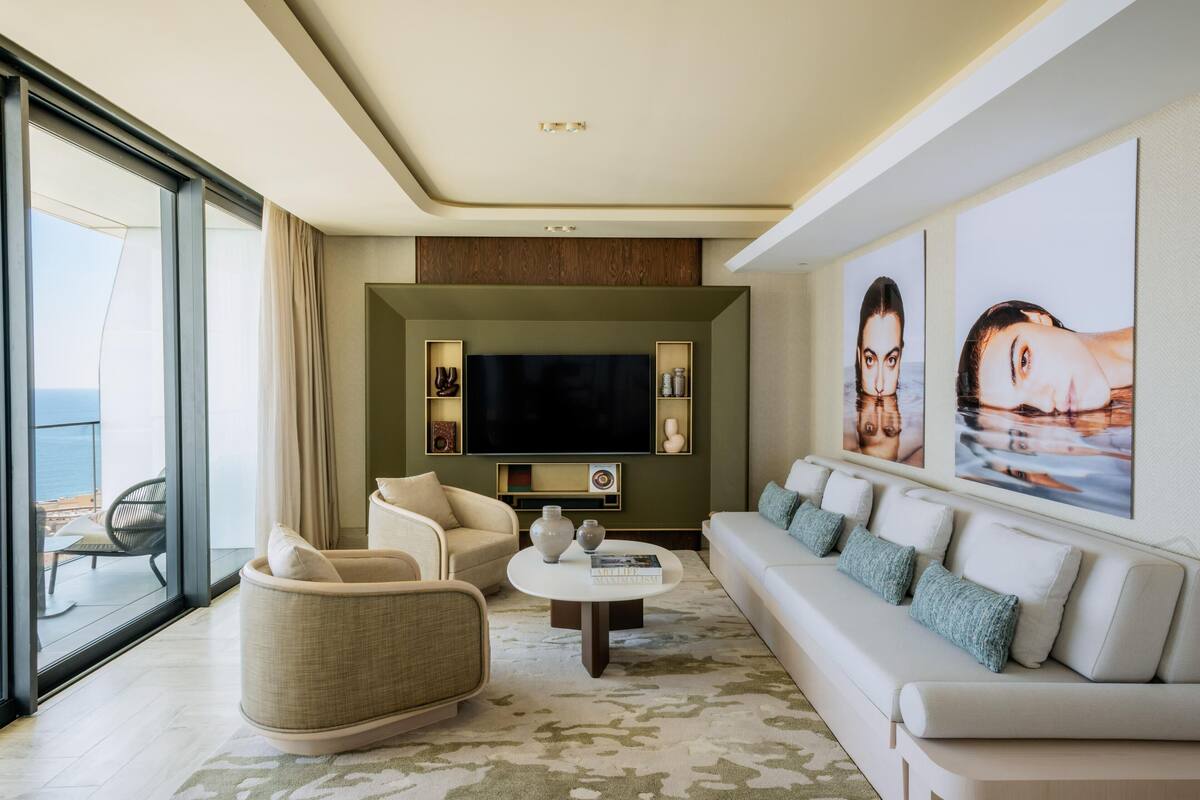 A modern living room with a large flat-screen TV, comfortable seating, and artwork on the walls.