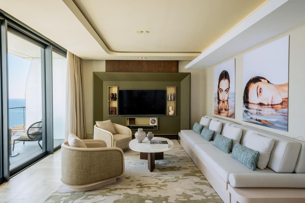 Uma sala de estar moderna com uma televisão de tela grande, assentos confortáveis e obras de arte nas paredes.