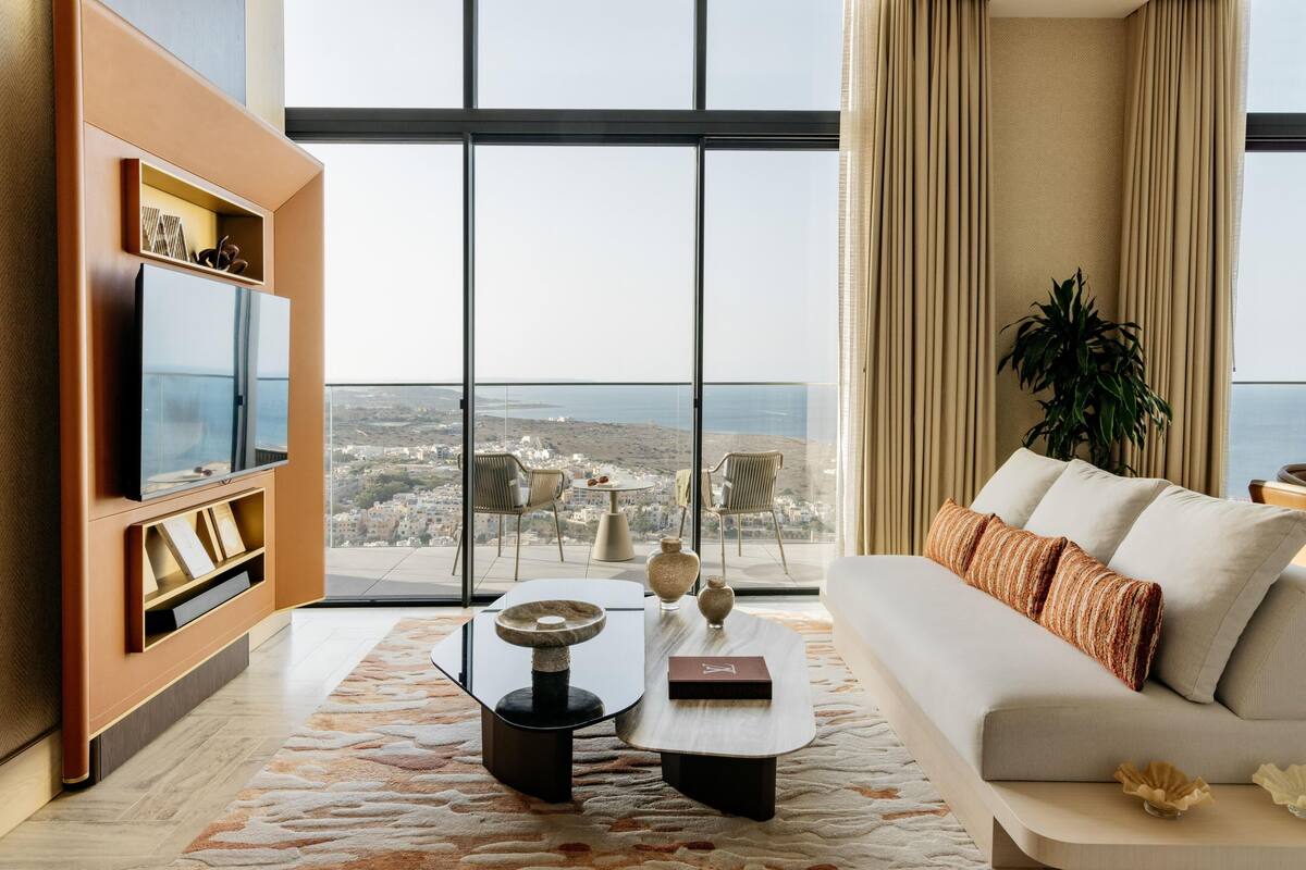 A modern living room with a large window, a sofa, a coffee table, and a TV.