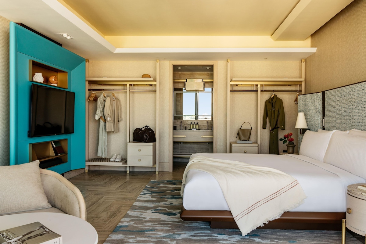 A hotel room with a bed, a TV, a closet, a bathroom, and a view.