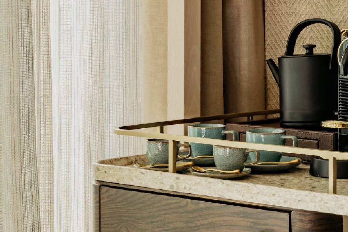A kitchen with a countertop, a kettle, and a tray holding cups and saucers.