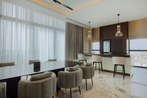 A modern dining area with a glass table, upholstered chairs, and a city view.