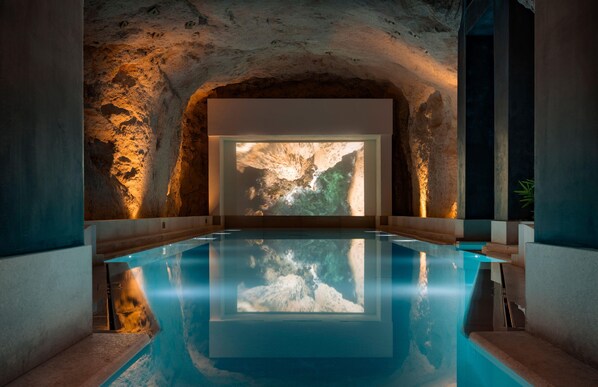 Piscina interior moderna con vista despejada a una estructura natural tipo cueva.