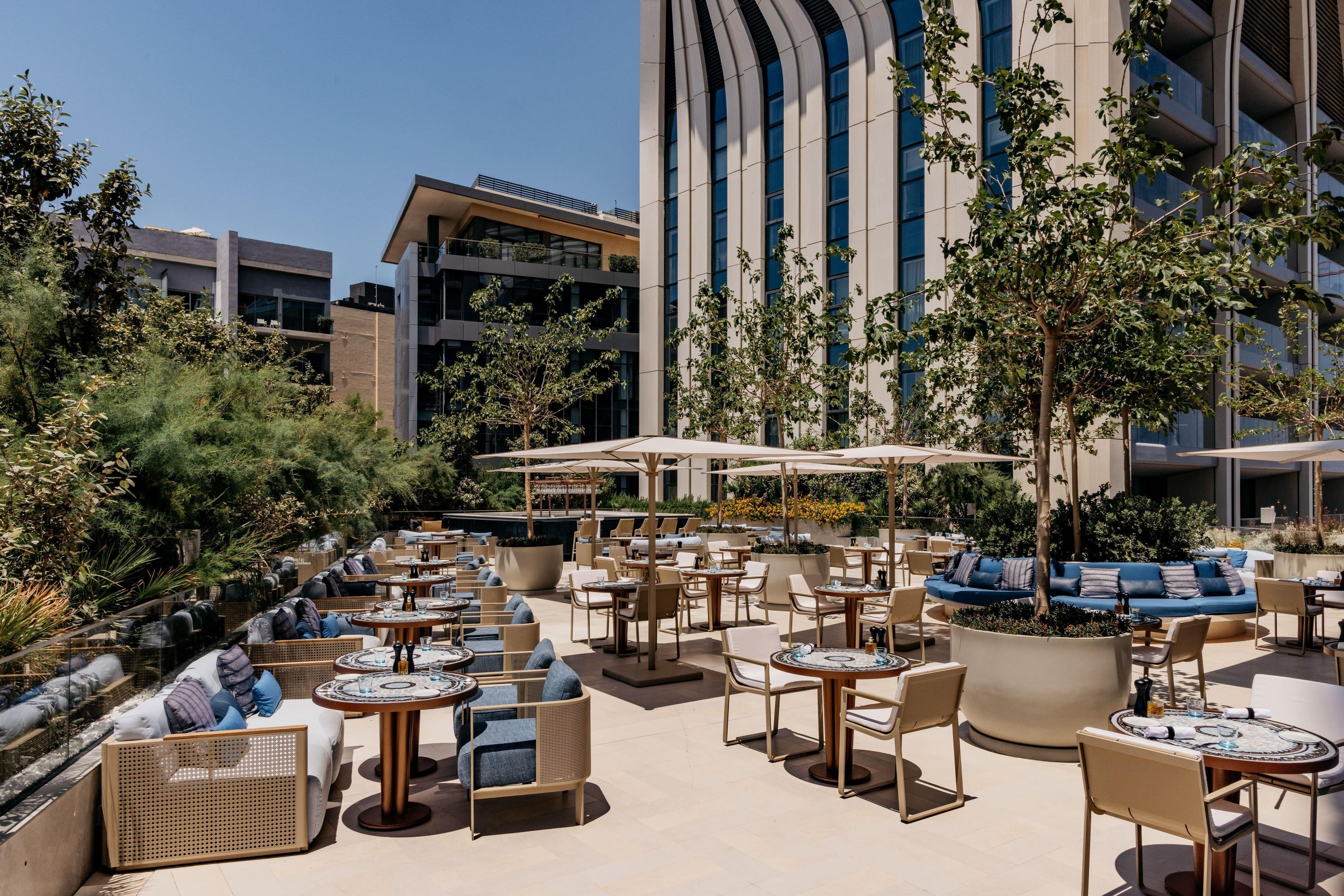 Terraza en la azotea con mobiliario exterior, piscina y un edificio moderno al fondo.