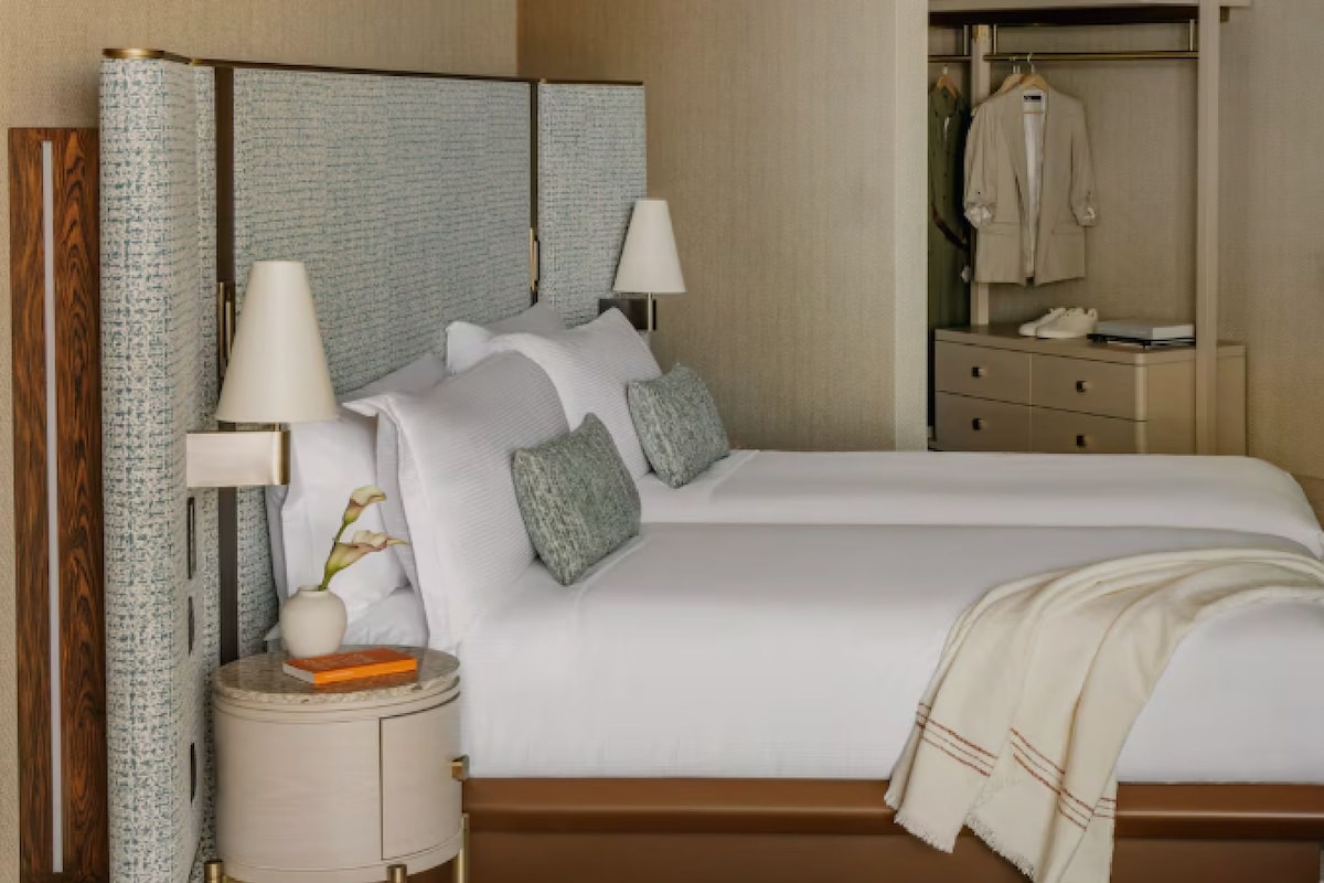 A hotel room with a large bed, bedside lamps, a nightstand, a wardrobe, and a mirror.