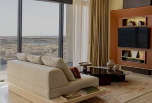 A modern living room with a sofa, a flat-screen TV, and a view of a cityscape.