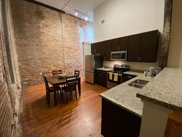 Kitchen features a stove, sink, and refrigerator, with a dining area nearby.