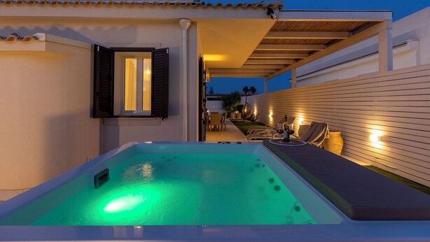 A spa area with a hot tub, outdoor seating, and a covered patio. - Villa Teresann con Jacuzzi riscaldata (Santa Maria del Focallo)
