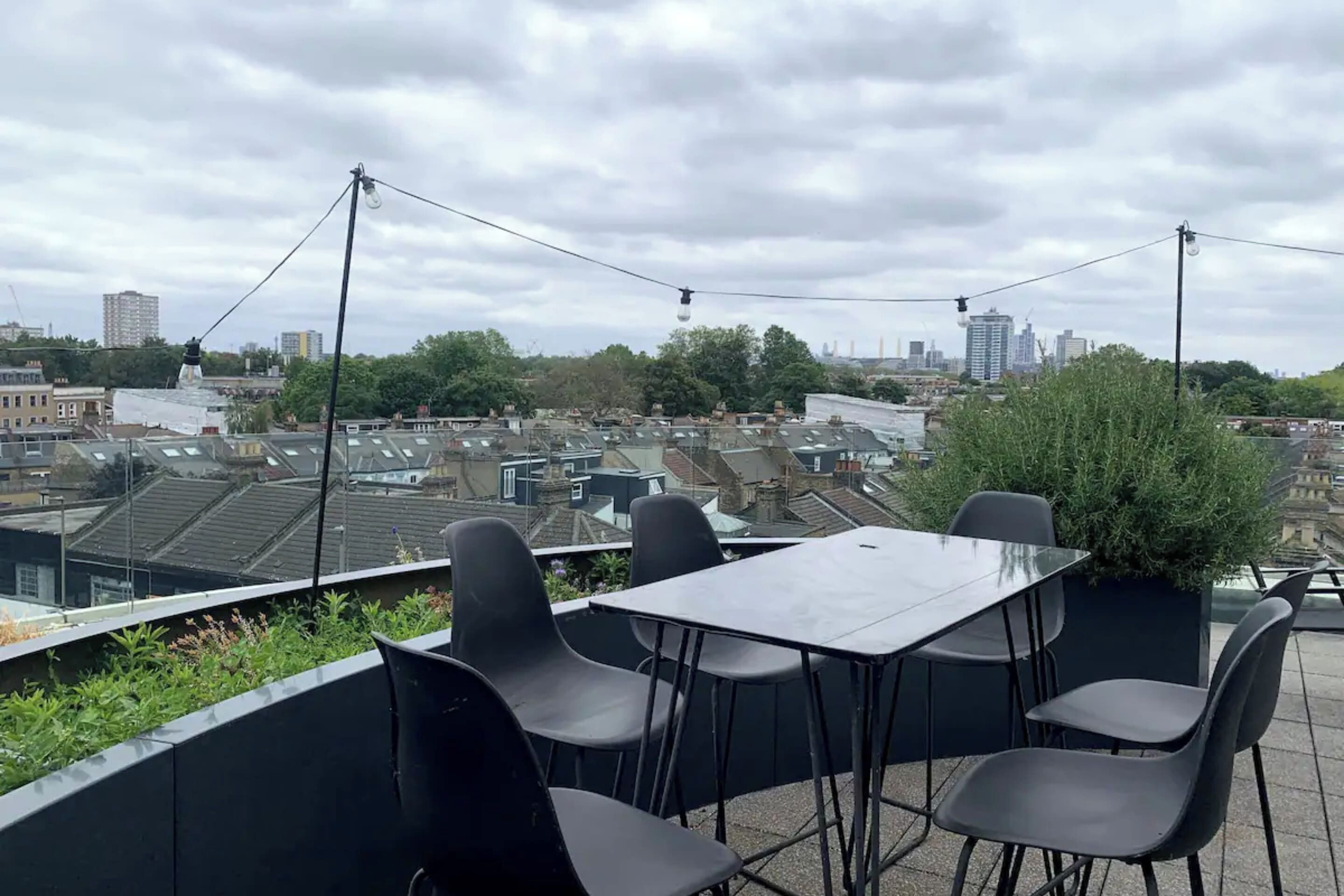 Une terrasse sur le toit, avec une table et des chaises, offrant une vue sur le paysage urbain.