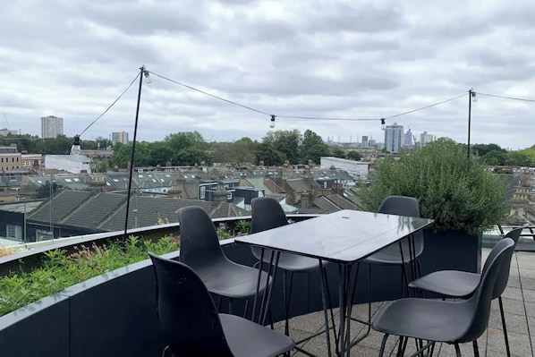En tagterrasse med et bord og stole, der giver udsigt over bybilledet.