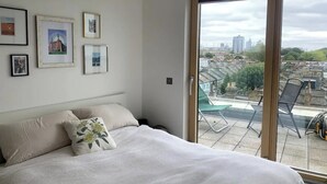 Quarto com uma cama, uma varanda com cadeiras e quadros nas paredes.