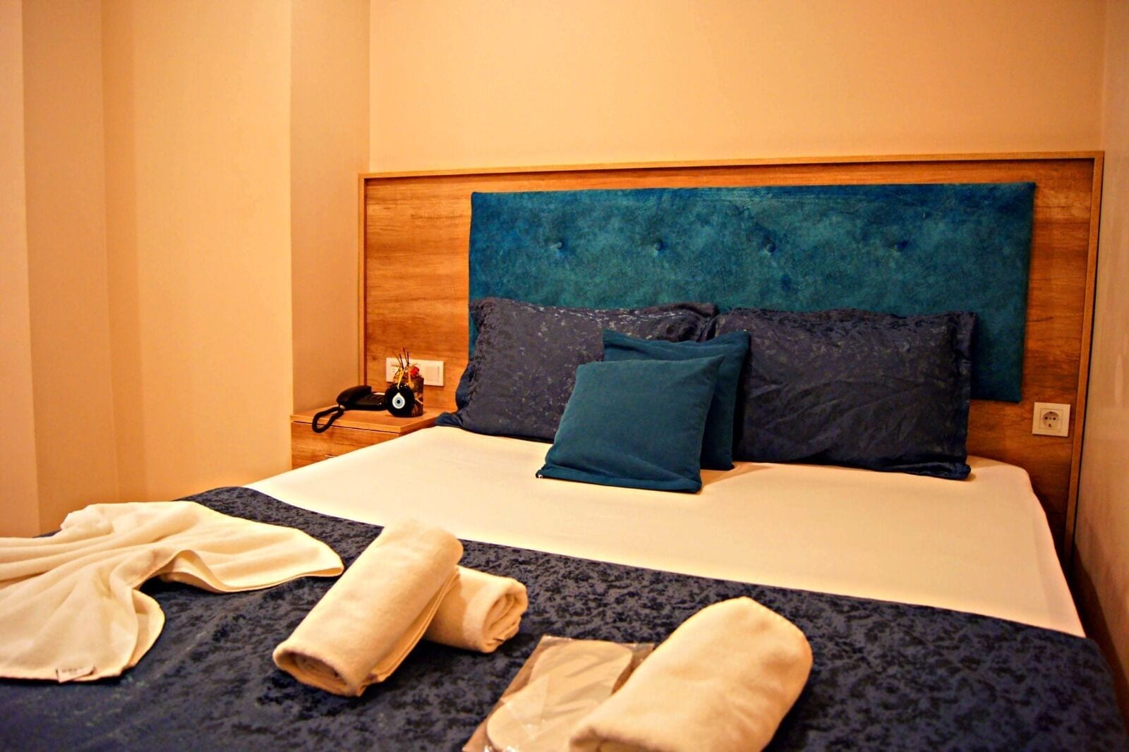 Una cama bien hecha con un cabecero azul, dos almohadas y una colcha.