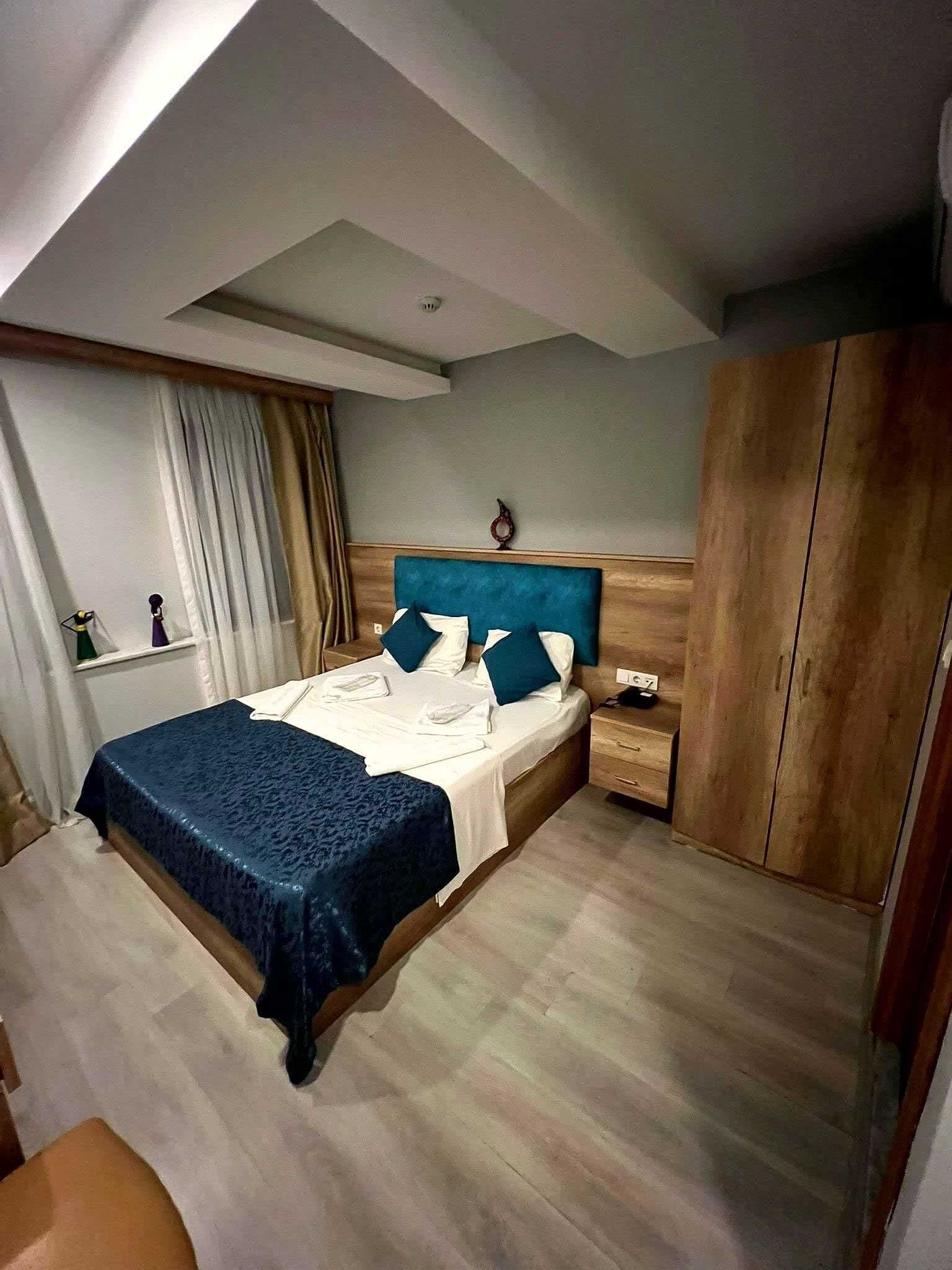 A bedroom with a bed, bedside tables, a wardrobe, and a window with curtains.