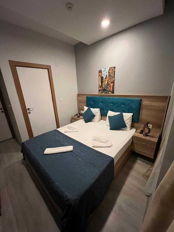 Une chambre à coucher bien rangée, avec un lit, des tables de chevet et un tableau accroché au mur.